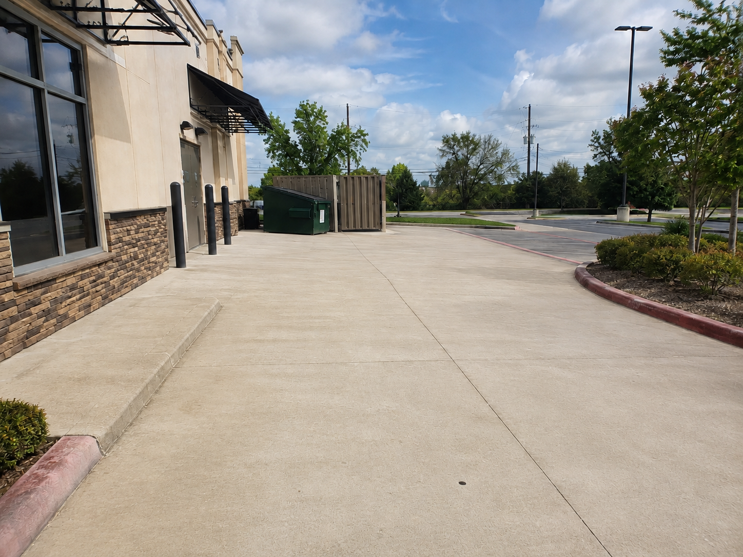 Commercial dumpster pad concrete being pressure washed